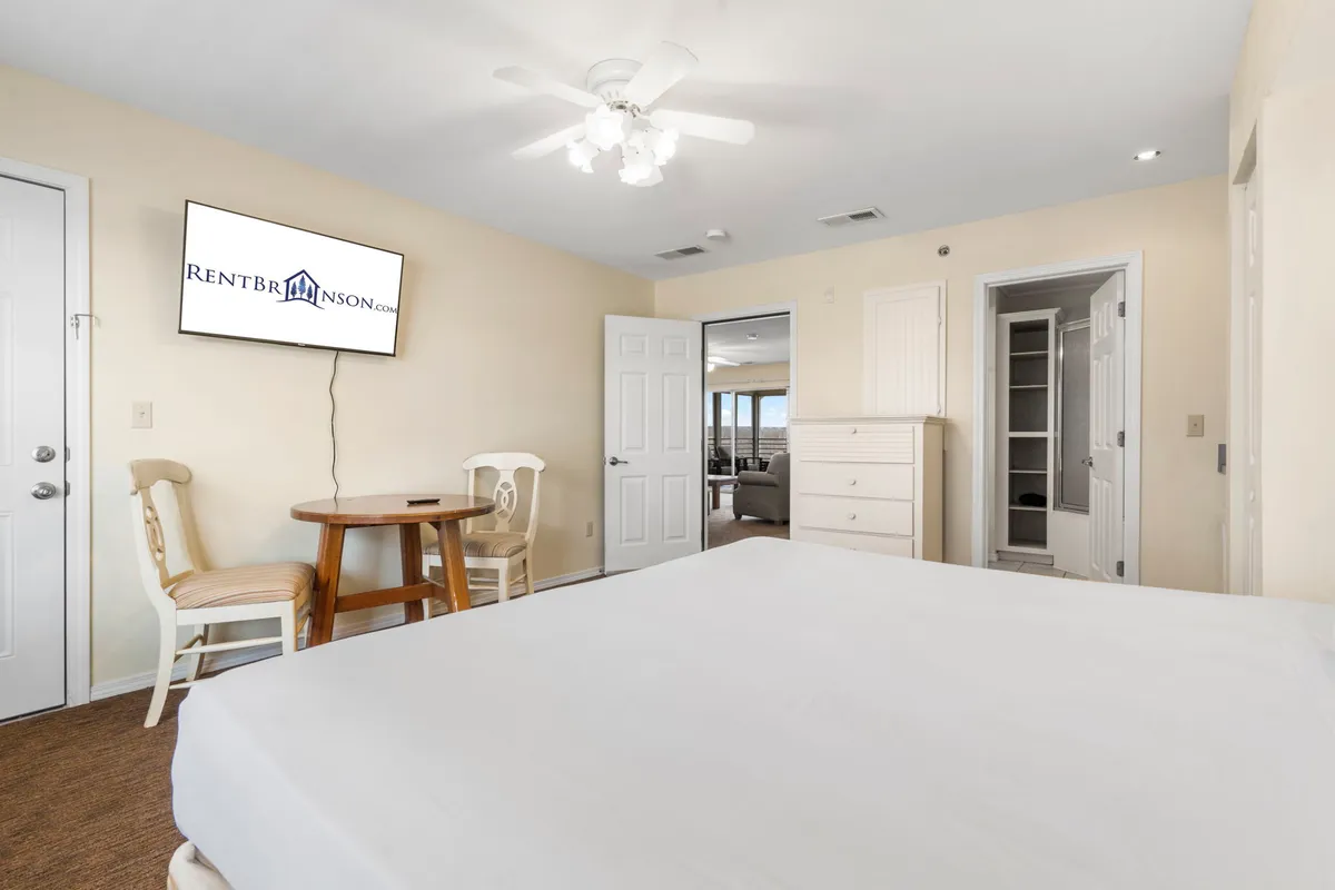 A spacious king bedroom with a plush bed, a flat-screen TV, a table and chairs for casual meals or work, and a dedicated dressing area. The room exudes comfort and privacy, making it ideal for restful nights.