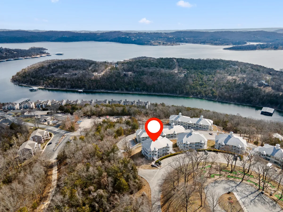 A panoramic exterior shot showcasing the tranquil lake, surrounding hills, and nearby residential buildings. The water is calm, the landscape inviting, and the scene evokes a sense of serenity and outdoor adventure.