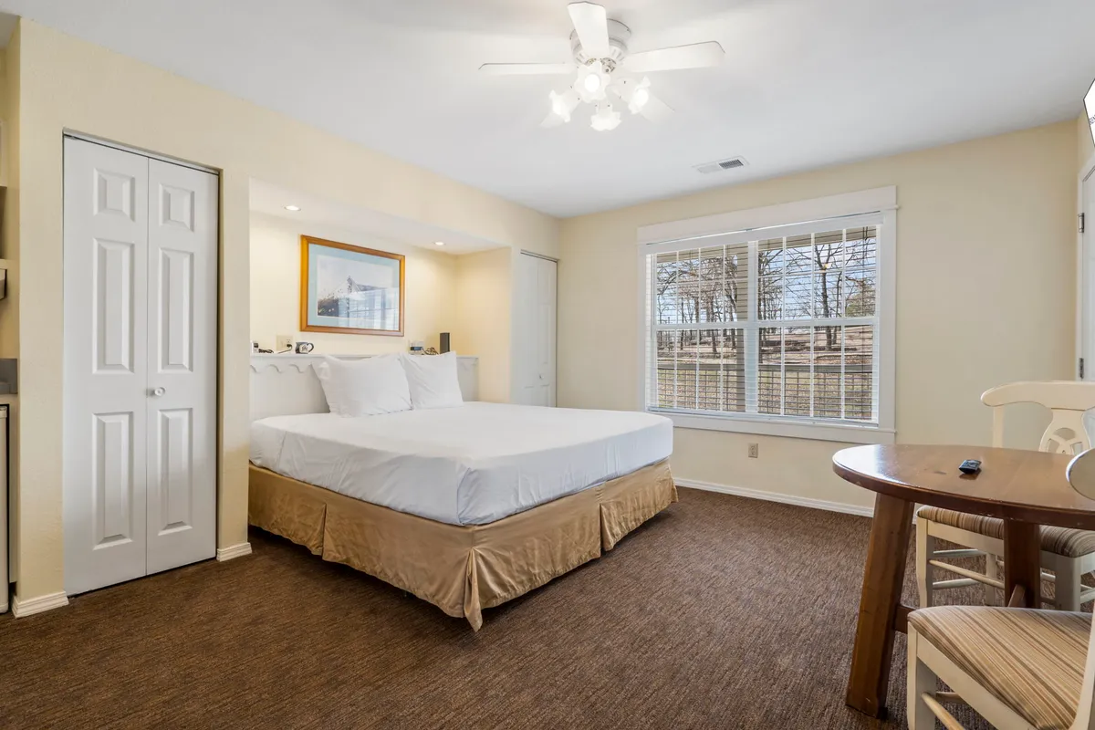 A serene bedroom with a comfortable bed, a window offering tranquil outdoor views, and a small table perfect for enjoying a morning coffee. The room is decorated in calm, inviting tones.