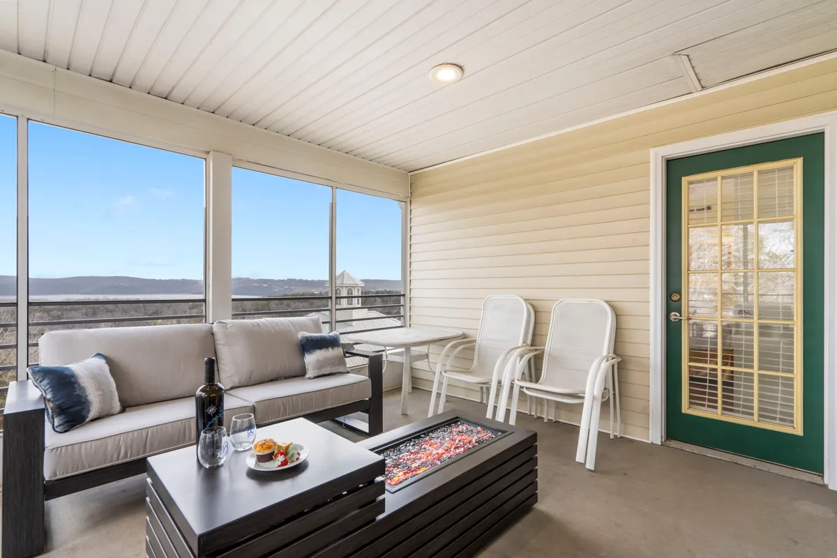 A comfortable seating area with a coffee table featuring decorative items, large windows that open up to a stunning lake view, and a relaxed, sociable vibe. Perfect for unwinding or sharing drinks as the sun sets.