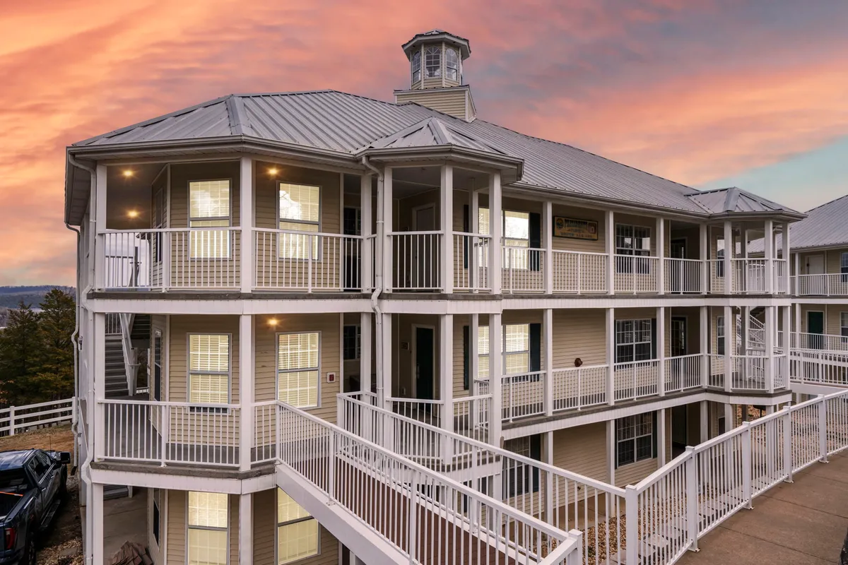 This exterior shot captures the architectural details of the Ozark Vista building at sunset, with visible balconies and an inviting sky. The scene hints at the serene lakeside environment and the opportunity to enjoy sunset views from the comfort of your private deck or balcony.