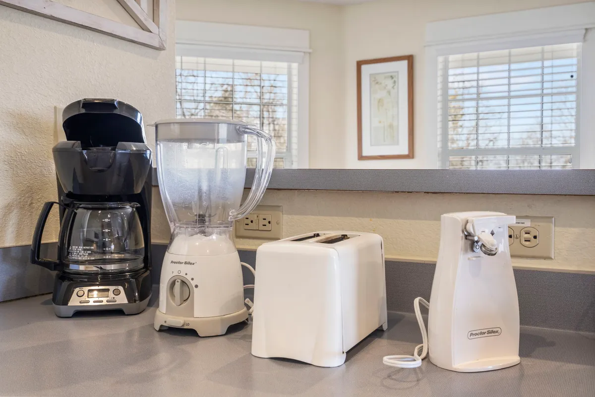 A compact kitchenette with a coffee maker, blender, toaster, and can opener arranged on the countertop, conveying functionality and convenience for guests needing a midnight snack or early-morning coffee.