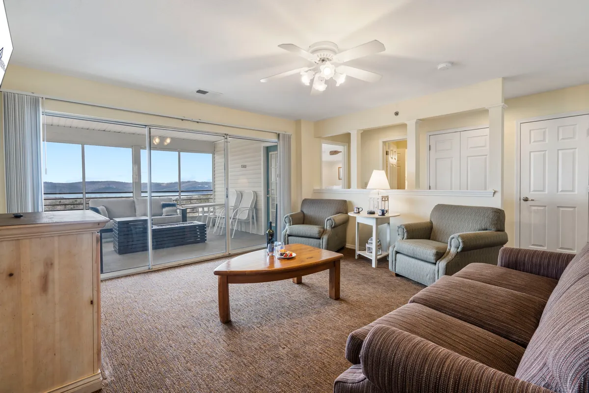 A cozy living room featuring comfortable seating, a spacious coffee table, and large sliding glass doors that open up to beautiful lake views. The room is arranged for conversation and relaxation, emphasizing togetherness and connection to the scenic outdoors.