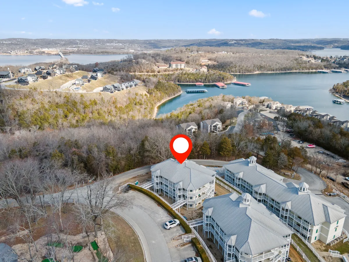 A tranquil lake view with surrounding homes and a winding road, evoking a peaceful and private retreat. The expansive water and gentle hills highlight the lakeside setting and the potential for sunset strolls or quiet moments by the water.