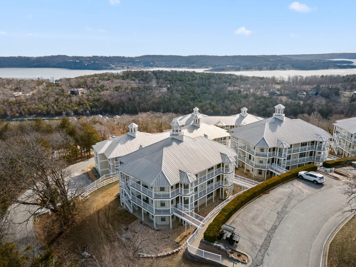 A tranquil exterior view of the resort’s multi-unit buildings set against a backdrop of lush landscaping and a lake. Paths wind through the property, offering scenic routes for leisurely walks and connecting to natural spaces.